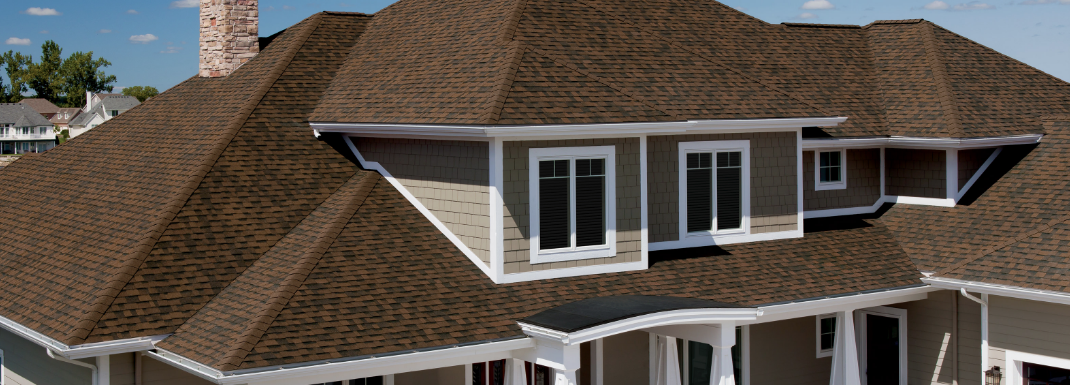 brown shingles on a large home with white trim