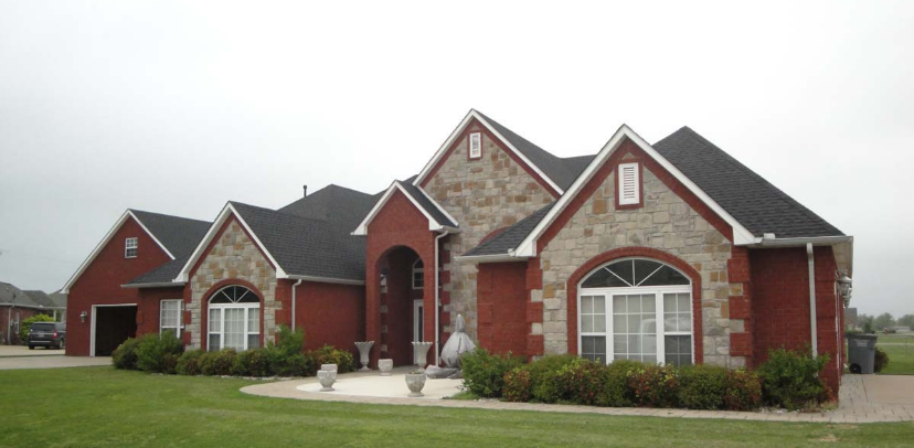 large red and grey stone home with a grey roof