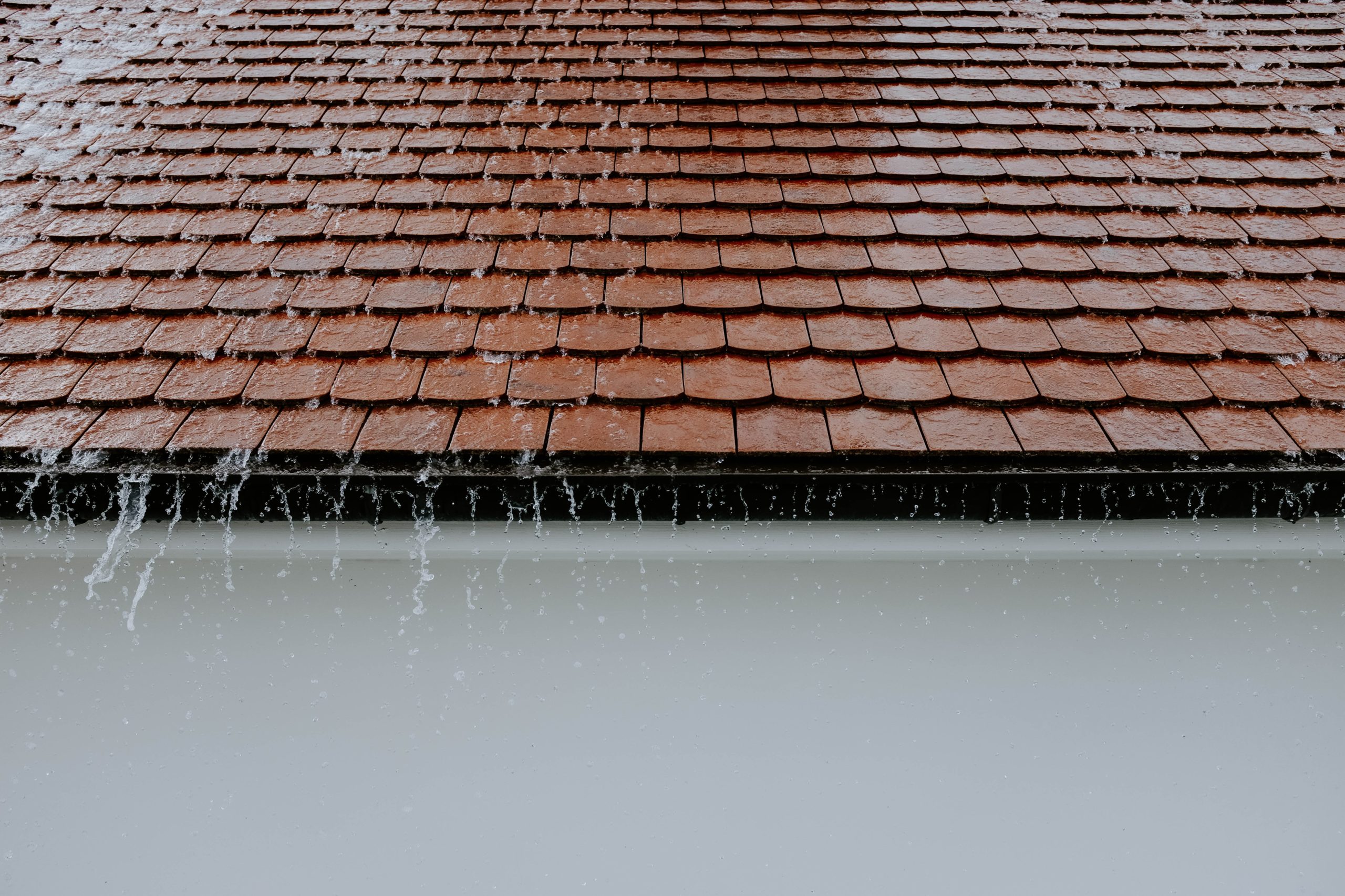 rain pouring down roof into gutters